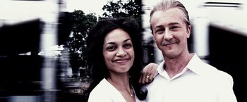 Movie still from “25th Hour” (2002), directed by Spike Lee – A man and a woman smile for a picture; Close Up shot, Low angle