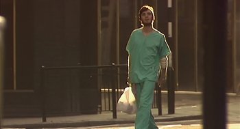 Movie still from “28 Days Later” (2002), directed by Danny Boyle – A man in a green scrub suit walking down the street; Wide shot, Low angle