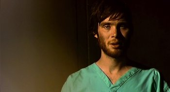 Movie still from “28 Days Later” (2002), directed by Danny Boyle – A man with a beard wearing a green shirt; Close Up shot, Low angle