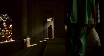 Movie still from “28 Days Later” (2002), directed by Danny Boyle – A man standing in a dark room with light shining on him; Wide shot, Low angle