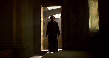 Movie still from “28 Days Later” (2002), directed by Danny Boyle – A man standing in a doorway in the sunlight; Wide shot, Low angle