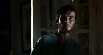 Movie still from “28 Days Later” (2002), directed by Danny Boyle – A man with a beard is standing in a room; Close Up shot, Low angle