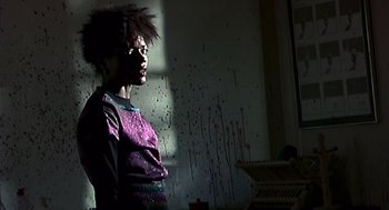 Movie still from “28 Days Later” (2002), directed by Danny Boyle – A woman standing in front of a wall with blood on it; Medium shot, Low angle