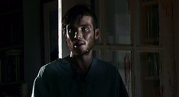 Movie still from “28 Days Later” (2002), directed by Danny Boyle – A man in a green shirt with blood all over his face; Close Up shot, Over the shoulder angle