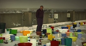 Movie still from “28 Days Later” (2002), directed by Danny Boyle – A man standing on top of a pile of pots; Wide shot, High angle