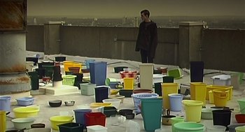 Movie still from “28 Days Later” (2002), directed by Danny Boyle – A man standing in front of a table full of pots and pans; Extreme Wide shot, High angle