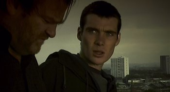 Movie still from “28 Days Later” (2002), directed by Danny Boyle – Two men standing next to each other in front of a building; Close Up shot, Low angle