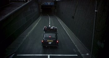 A car with luggage strapped to the back of it driving through a tunnel