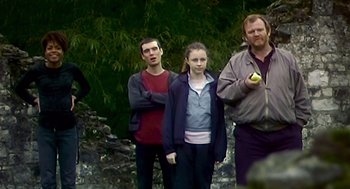 Movie still from “28 Days Later” (2002), directed by Danny Boyle – A group of people standing next to each other near trees; Medium shot, Over the shoulder angle