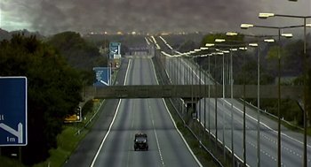 Movie still from “28 Days Later” (2002), directed by Danny Boyle – A truck driving down a highway under an overpass; Extreme Wide shot, High angle