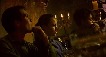 Movie still from “28 Days Later” (2002), directed by Danny Boyle – Two people sitting in front of candles in a dimly - lit room; Medium shot, Low angle