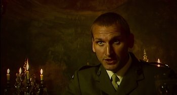 Movie still from “28 Days Later” (2002), directed by Danny Boyle – A man wearing a green uniform holding a candle; Close Up shot, Over the shoulder angle