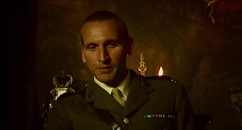 Movie still from “28 Days Later” (2002), directed by Danny Boyle – A man in a military uniform standing in front of candles; Close Up shot, Over the shoulder angle