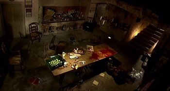 Movie still from “28 Days Later” (2002), directed by Danny Boyle – A table covered in blood in a room with other items; Wide shot, High angle