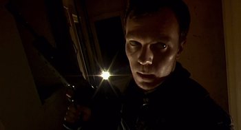 Movie still from “28 Days Later” (2002), directed by Danny Boyle – A man is looking at the camera with a flashlight; Close Up shot, Low angle