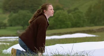 Movie still from “28 Days Later” (2002), directed by Danny Boyle – A young girl sitting on the ground in the grass; Medium shot, Low angle