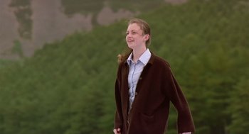Movie still from “28 Days Later” (2002), directed by Danny Boyle – A man in a brown jacket is walking outside; Medium shot, Low angle
