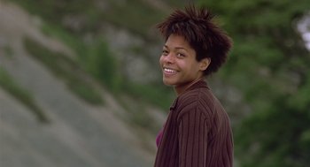 Movie still from “28 Days Later” (2002), directed by Danny Boyle – A young woman smiles brightly while standing in front of trees; Close Up shot, Low angle