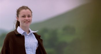 Movie still from “28 Days Later” (2002), directed by Danny Boyle – A young woman standing in front of a green mountain; Medium shot, Low angle