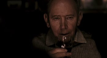 Movie still from “28 Weeks Later” (2007), directed by Juan Carlos Fresnadillo – An older man holding a glass of red wine; Close Up shot, Over the shoulder angle