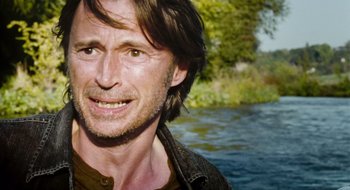 Movie still from “28 Weeks Later” (2007), directed by Juan Carlos Fresnadillo – A person wearing a jacket near a body of water; Close Up shot, Over the shoulder angle