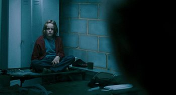 Movie still from “28 Weeks Later” (2007), directed by Juan Carlos Fresnadillo – A girl sitting on steps in a dark room; Medium shot, Over the shoulder angle