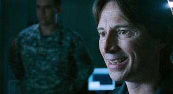 Movie still from “28 Weeks Later” (2007), directed by Juan Carlos Fresnadillo – A person smiling with a man in the background; Close Up shot, Over the shoulder angle