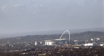 A view of a city from a hill with a bridge in the background