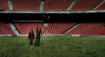 Movie still from “28 Weeks Later” (2007), directed by Juan Carlos Fresnadillo – Two women are standing in an empty stadium; Extreme Wide shot, High angle
