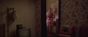 Movie still from “3 Women” (1977), directed by Robert Altman – A woman standing in front of a bathroom mirror looking in the mirror; Medium shot, High angle