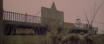 Movie still from “3 Women” (1977), directed by Robert Altman – A sign that reads " rodeo city " on top of a building; Extreme Wide shot, Low angle