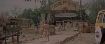Movie still from “3 Women” (1977), directed by Robert Altman – A little girl standing in front of a sign for santa fé trail; Extreme Wide shot, High angle