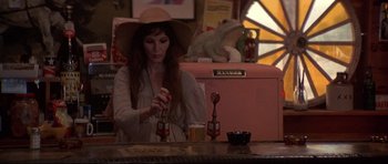 Movie still from “3 Women” (1977), directed by Robert Altman – A woman sitting at a bar with a hat on; Medium shot, Over the shoulder angle
