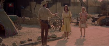 Movie still from “3 Women” (1977), directed by Robert Altman – A man and a woman standing next to each other on a dirt road; Wide shot, Over the shoulder angle