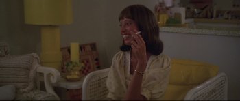 Movie still from “3 Women” (1977), directed by Robert Altman – A woman talking on a cell phone while sitting at a table; Medium shot, Over the shoulder angle