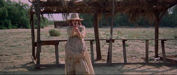 Movie still from “3 Women” (1977), directed by Robert Altman – A woman standing in a field taking a picture with a cell phone; Wide shot, Low angle