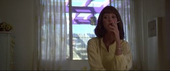 Movie still from “3 Women” (1977), directed by Robert Altman – A woman smoking a cigarette in front of a window; Medium shot, Low angle