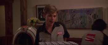 Movie still from “3 Women” (1977), directed by Robert Altman – A young man is standing in front of a bunch of soda cans; Close Up shot, Low angle