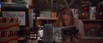 Movie still from “3 Women” (1977), directed by Robert Altman – A woman sitting at a table reading a magazine; Medium shot, Over the shoulder angle