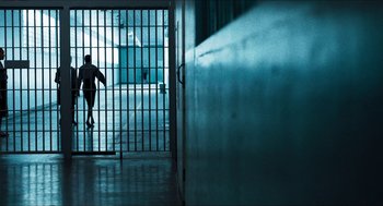 Movie still from “3 from Hell” (2019), directed by Rob Zombie – A person walking through a jail cell with bars; Extreme Wide shot, High angle