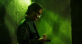 Movie still from “3 from Hell” (2019), directed by Rob Zombie – A man in a green uniform looking at his cell phone; Medium shot, Low angle