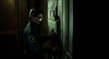 Movie still from “3 from Hell” (2019), directed by Rob Zombie – A woman in a uniform is looking into a door; Medium shot, Over the shoulder angle