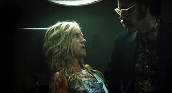 Movie still from “3 from Hell” (2019), directed by Rob Zombie – A woman sitting in front of a man in a chair; Close Up shot, Over the shoulder angle