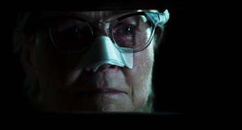 Movie still from “3 from Hell” (2019), directed by Rob Zombie – An older man wearing glasses and a paper mask; Close Up shot, Low angle