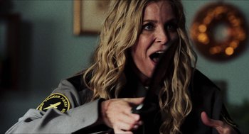 Movie still from “3 from Hell” (2019), directed by Rob Zombie – A woman holding a remote in her hand; Close Up shot, Over the shoulder angle