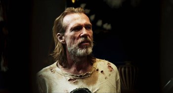 Movie still from “3 from Hell” (2019), directed by Rob Zombie – A man with long hair and a beard wearing a white shirt; Close Up shot, Over the shoulder angle