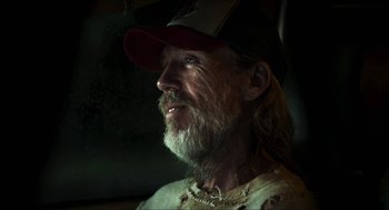 Movie still from “3 from Hell” (2019), directed by Rob Zombie – A man with long hair and a beard wearing a baseball cap; Close Up shot, Low angle