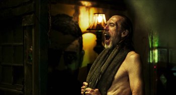 Movie still from “3 from Hell” (2019), directed by Rob Zombie – A man with a towel around his neck is yawning; Medium shot, Low angle