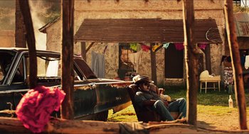 Movie still from “3 from Hell” (2019), directed by Rob Zombie – A man sitting in a chair under a wooden structure; Wide shot, Low angle