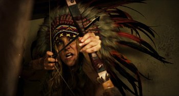 Movie still from “3 from Hell” (2019), directed by Rob Zombie – A man in a native american headdress holding a bow and arrow; Close Up shot, Over the shoulder angle